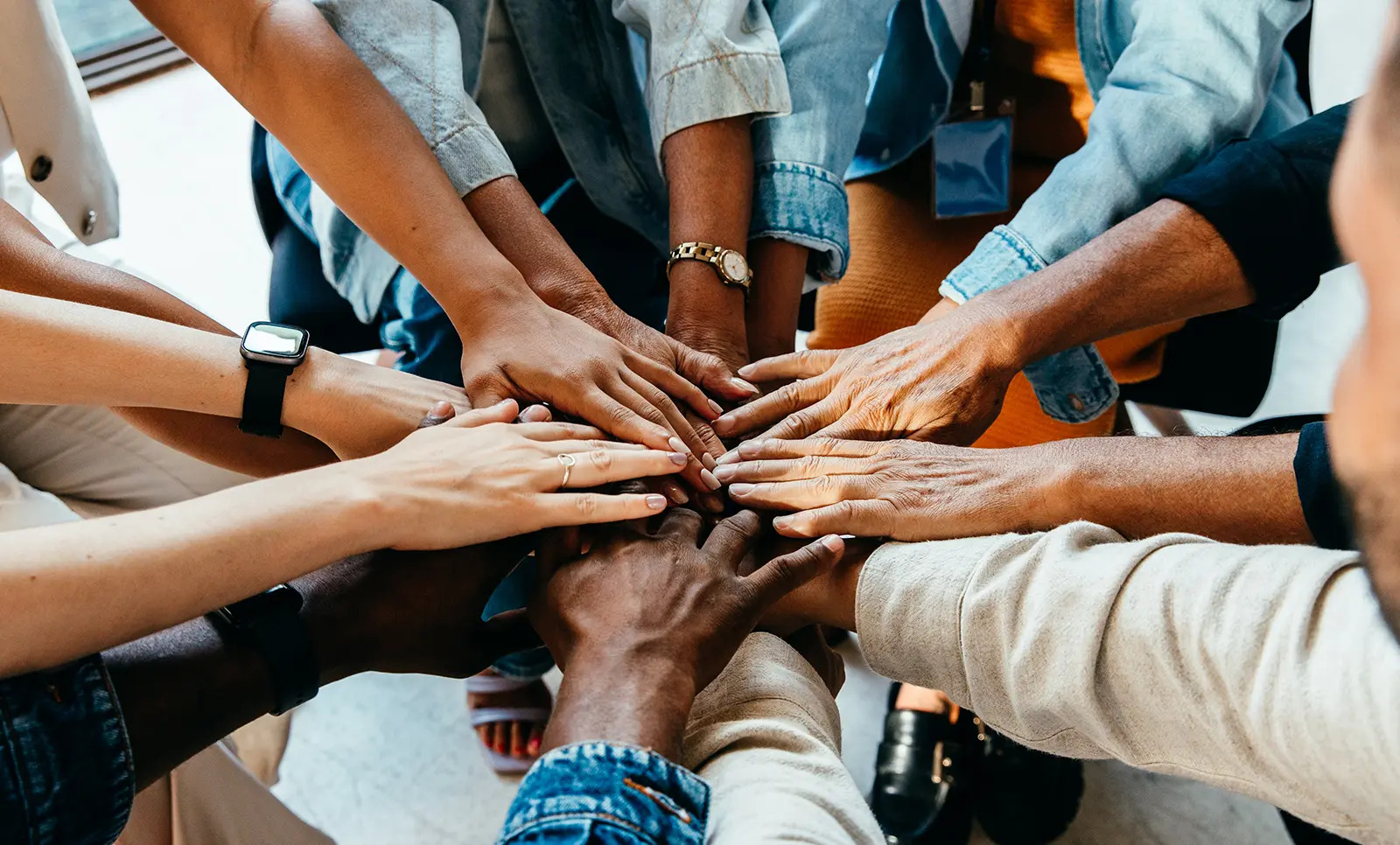 A group of diverse people putting their hands together in a circle